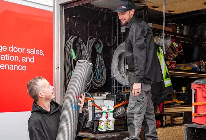 Two The Door Company seasoned installers and repairmen loading their truck with springs and other parts before going on an urgent repair of an agricultural door in Ottawa, Eastern Ontario